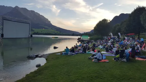 Filmvorf&uuml;hrung im Freien, Kinoleinwand im Wasser und Zuseher am Ufer.
